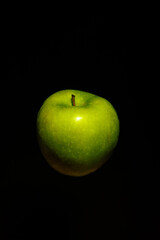 Fresh whole green apple levitating against dark black backdrop, showing natural farming, organic health, wellness diet, and sport lifestyle energy