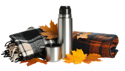 Metal thermos and mug surrounded by autumn leaves and warm plaid blankets on transparent background