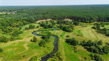 Aerial drone view of colorful kayaks floating along the winding Liswarta River, river surrounded by lush green meadows and summer nature landscape. Kayaking on river in Poland. Kayaks on a river