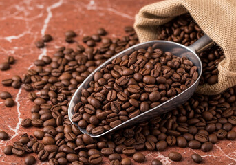 Roasted coffee beans spread across a surface, highlighting rich brown tones, texture, and aroma in a detailed macro shot.
