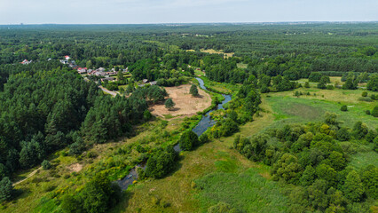 Aerial drone view of colorful kayaks floating along the winding Liswarta River, river surrounded by lush green meadows and summer nature landscape. Kayaking on river in Poland. Kayaks on a river