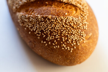 A close-up view of a sesame seed topped artisan bread loaf, showcasing its rich golden crust and texture.