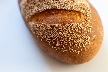 Close-up of a fresh, crusty bread loaf topped with sesame seeds, showcasing its golden brown color and texture.