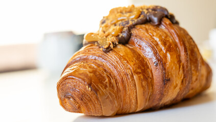 A deliciously flaky croissant topped with chocolate and caramel, perfect for breakfast or a sweet treat.