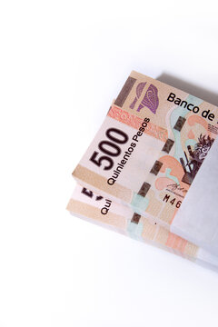Primer plano de billetes de 500 pesos mexicanos, apilados sobre un fondo blanco, vista superior
Close-up of 500 Mexican peso bills, stacked on a white background, top view