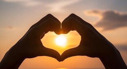 Hands forming a heart shape in front of the sun, golden hour glow