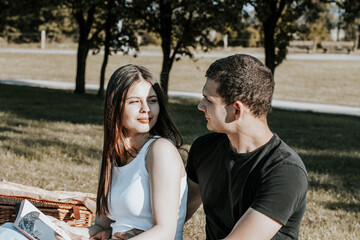 Fototapeta premium A young couple looks at each other on a picnic in the park.