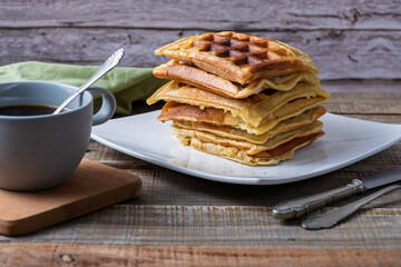Breakfast consisting of a stack of waffles and a cup of coffee.