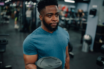 Young determined athlete lifting weights in modern gym
