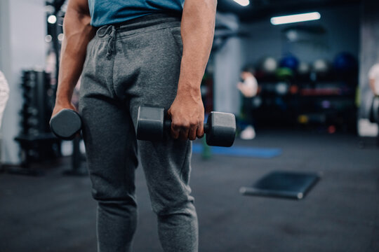 Bodybuilder lifting weights, exercising biceps in modern gym