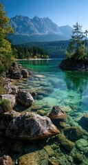 Fototapeta premium Crystal-clear alpine lake, shallows with rocks, forested shore, mountains in background under a vibrant blue sky