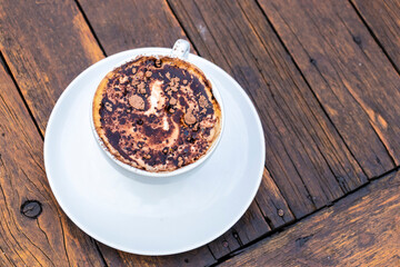 A cup of cappuccino with chocolate powder on a rustic wooden table in Brazil. Perfect for illustrating indulgence, simple pleasures, and coffee culture.