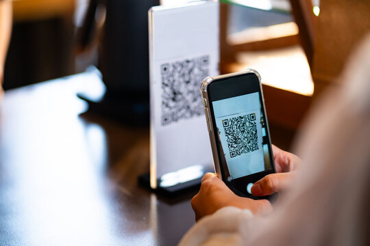Customer buy coffee using electronic credit card on smartphone app scan QR code making online banking payment at cashier counter. Small business entrepreneur coffee shop barista cafe restaurant.