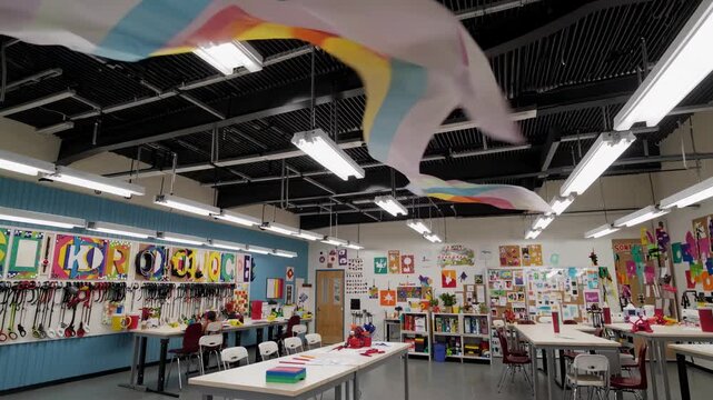 Colorful Fabric Swirling in a Creative Makerspace, Featuring Vibrant Decorations and Art Supplies on Walls and Tables. The Fabric's Motion Adds Dynamic Energy to the Space