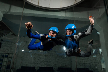 A male instructor teaches a woman how to fly in a wind tunnel. Free fall simulator.