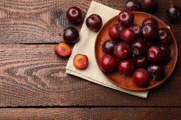 Ripe cherry plums on wooden table, flat lay. Space for text