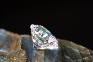 One shiny diamond on stone against black background, macro view