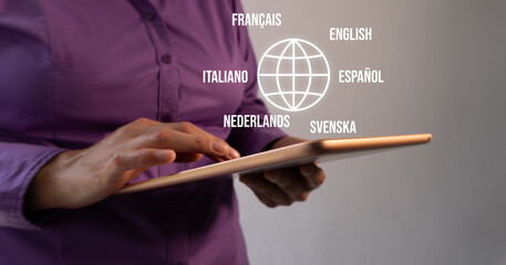 Machine translation of language. Businesswoman interacting with a tablet with a globe icon and several languages around it.