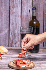 Close-up of a wine glass and a transparent sheet of Iberian ham, highlighting textures and amber colors