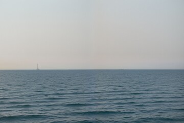 Obraz premium Calm Ocean Horizon with Oil Rig and Soft Sky Background at Dusk