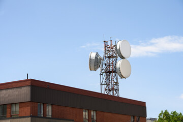 Old telephone company central office building with a lattice tower and round microwave drum backhaul antenna, rural southwest America
