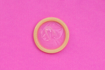 Condom on pink paper background.