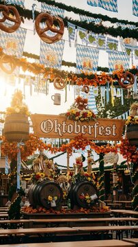 Oktoberfest sign at a traditional German beer festival. Autumn celebration with barrels, pretzels, and Bavarian decorations at sunset.