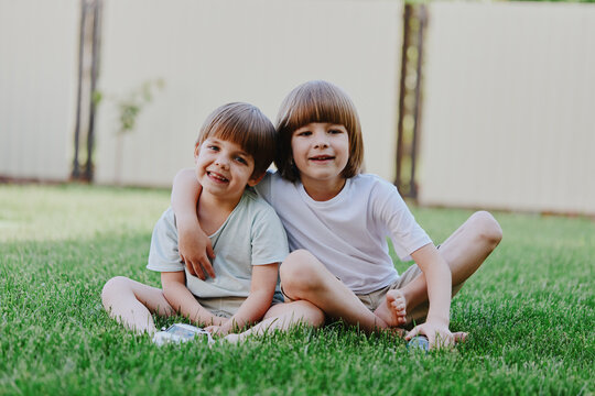 Cheerful children embracing in a sunny garden, smiling joyfully while enjoying outdoor play. Perfect moment of childhood happiness and bonding.