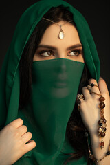 Naklejka premium Mystical Woman in Green Veil With Beads and Pearl Jewelry in Studio