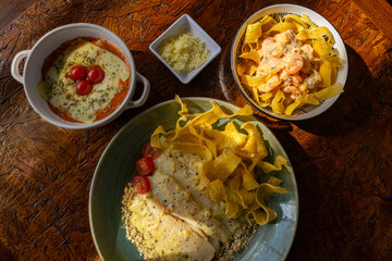 Top view of a rustic restaurant table with a variety of gourmet Colombian fusion dishes in direct sunlight, creating a warm and hearty feast.