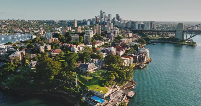 Australia, Sydney: Kirribilli suburb with lush greenery, elegant homes houses, and iconic Sydney Harbour Bridge gracing the horizon. Modern cityscape architecture. Drone flight aerial view footage