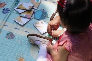 A girl is being taught to put together a puzzle in the shape of the Indonesian national symbol, the Garuda bird
