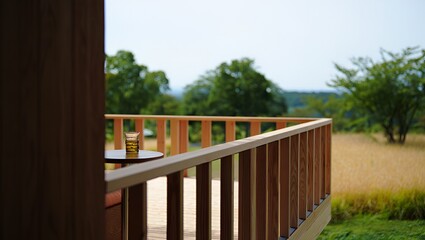 A serene veranda scene showcases wood railing, nature backdrop, a drink, and soft, diffused light.