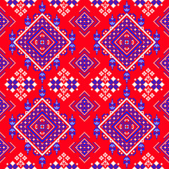A seamless geometric and floral pattern featuring diamond shapes and symmetrical flower motifs in blue, white, and orange on a vibrant red background. Inspired by traditional textile designs, 