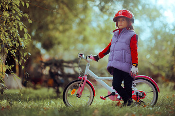 Fototapeta na wymiar Portrait of a Young girl Enjoying Nature Ridding Her Bike. Active child posing next to her bicycle 