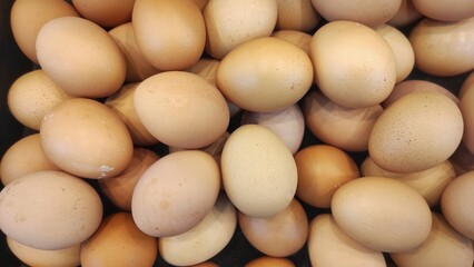 Fresh brown eggs neatly stacked inside a black basket at the supermarket, highlighting their natural shells and simple presentation for everyday use.