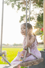 The girl sitting in a swing.