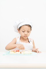 The girl is studying cooking using a sandwich knife on the white background.