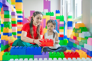The mother is teaching her daughter to learn to play toys, creating a shape according to imagination.