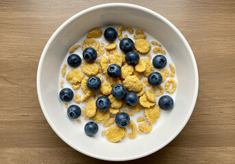 Flat lay of cereal with milk and fresh blueberries in bowl