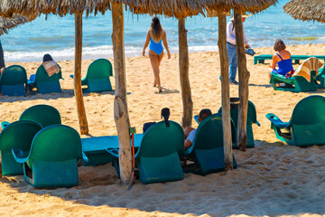 Tourists enjoy a private beach club with chairs and straw hut cabanas on the Golden Zone in Mazatlan, Mexico.
