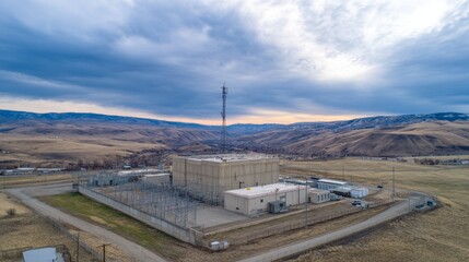 Aerial view of secure nuclear waste storage facility with warning signs and containment structures in barren landscape under cloudy sky. Environmental safety and hazardous material management concepts