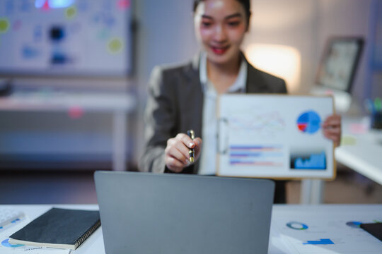 Businesswoman holding financial charts and graphs while having a video conference on laptop computer