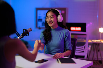 Female podcasters greeting, handshaking after recording professional broadcast in contemporary sound studio