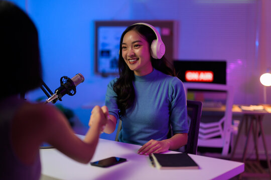 Female podcasters greeting, handshaking after recording professional broadcast in contemporary sound studio
