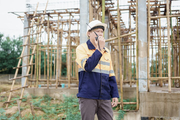 Construction workers wearing hard hats and reflective vests are working on a construction site and inspecting the structure of a house.