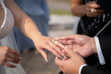 Groom placing wedding ring on bride finger during ceremony.