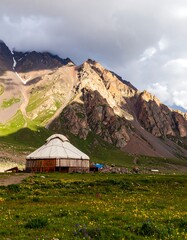 Mountainous landscape with a yurt in a grassy field
