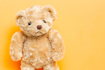 Cute brown teddy bear plush toy on orange background.