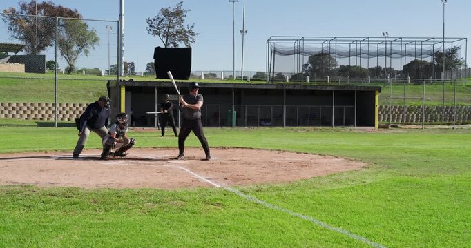 Pitcher delivering pitch, man swinging bat and racing to first base at baseball field, copy space